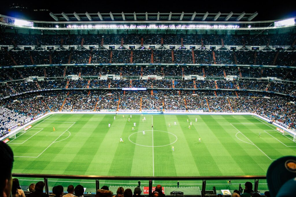 Voetbalstadion bij avond met verlichte tribunes vol supporters