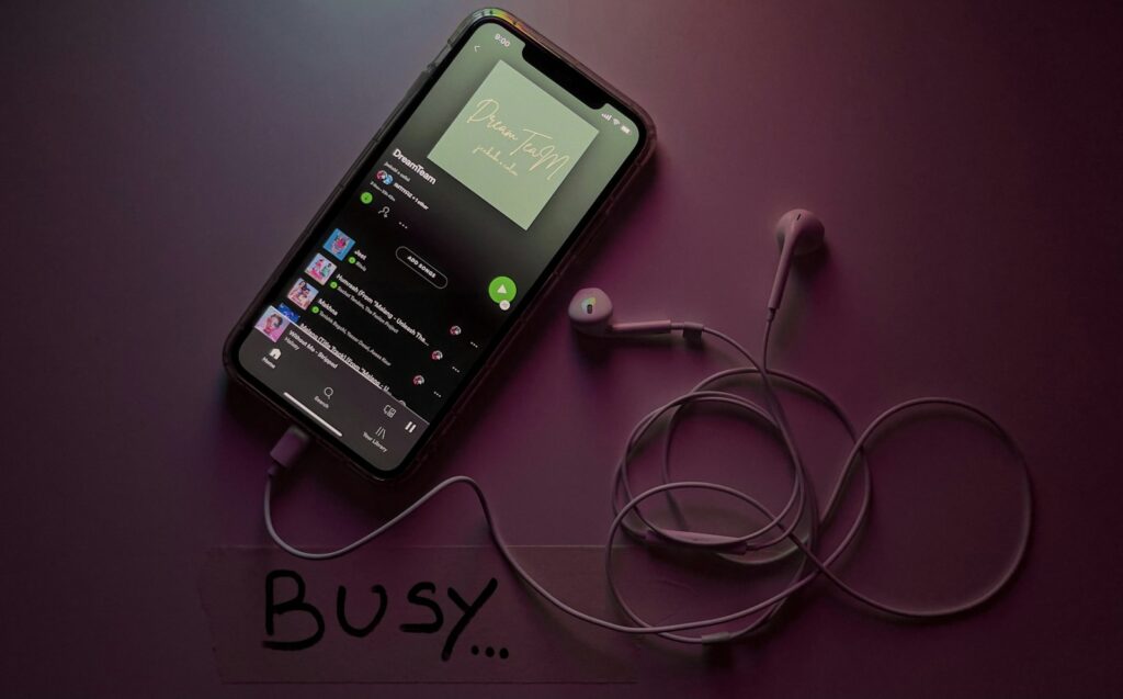 Smartphone met podcastapp naast oordopjes