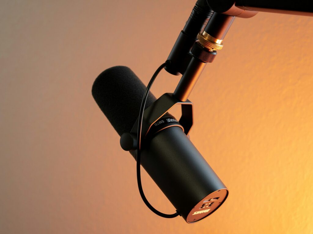 Microfoon en koptelefoon in een warm verlichte podcaststudio